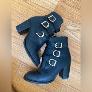 Black leather heeled boots with gold buckles